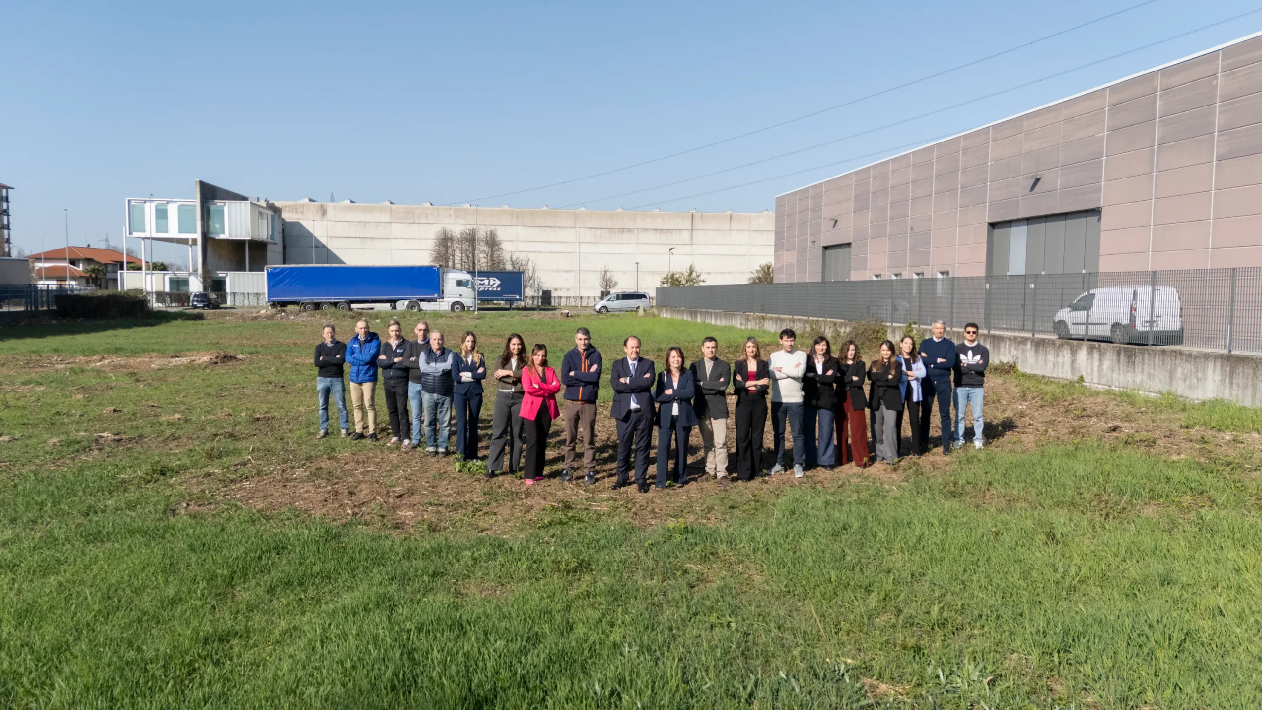 Foto dell'intero team Casalino Engineering in un campo vuoto in cui verrà costruitto il nuovo ufficio